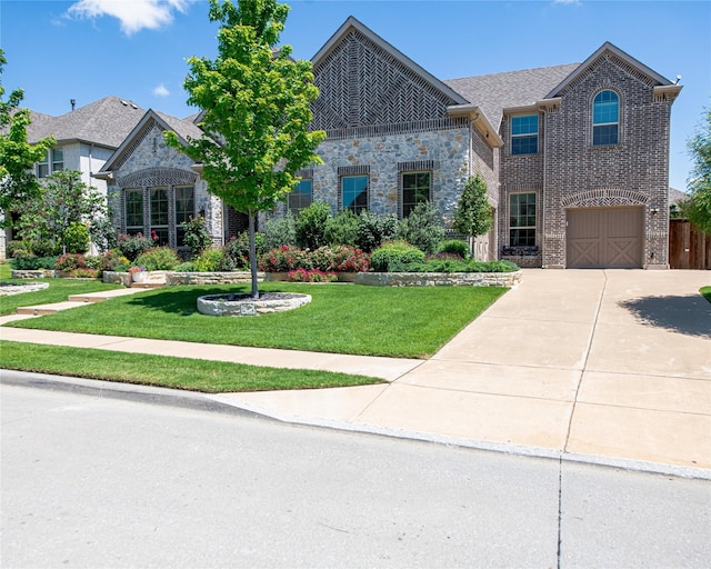 2624 Seabiscuit Rd, Celina, TX 75009 - french country inspired facade featuring concrete driveway, a front yard, brick siding, stone siding, and an attached garage