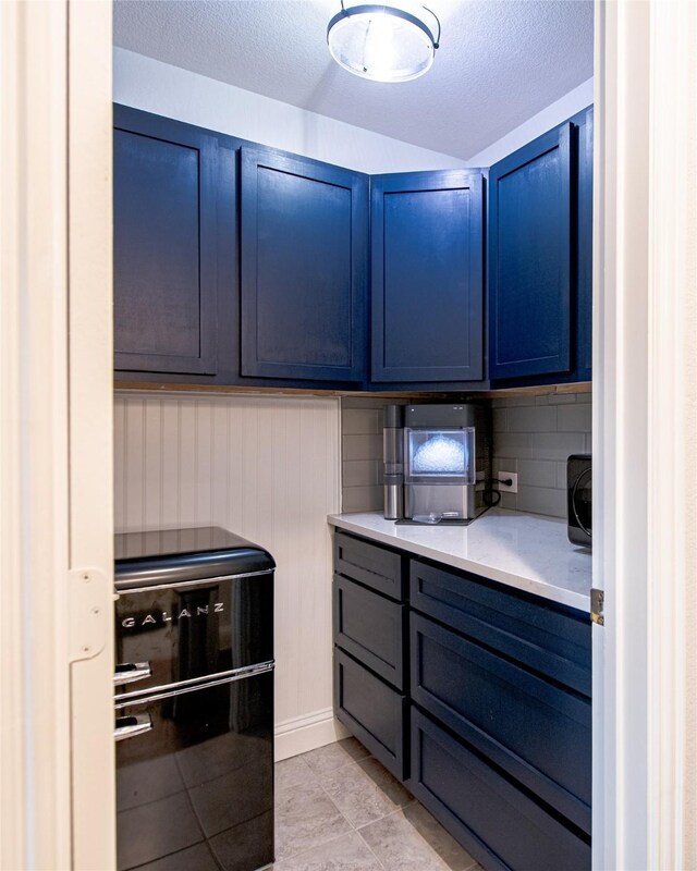 2624 Seabiscuit Rd, Celina, TX 75009 - kitchen featuring blue cabinetry, light countertops, decorative backsplash, a textured ceiling, and light tile patterned flooring