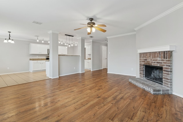 1812 Elk Lake Trl, Justin, TX 76247 - unfurnished living room featuring a ceiling fan, a chandelier, a fireplace, ornamental molding, and light wood-type flooring