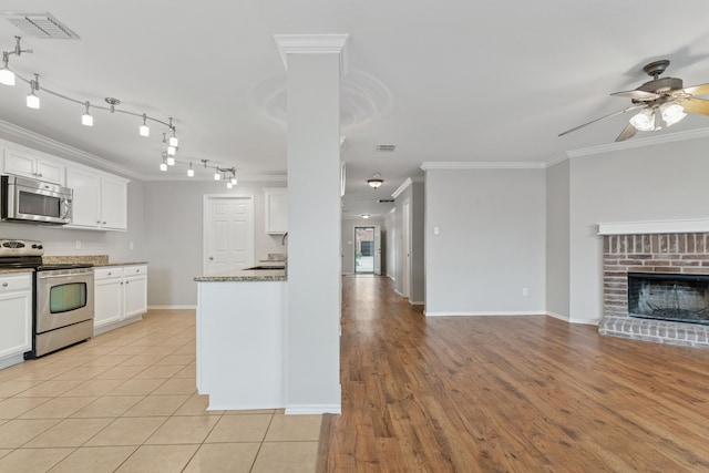 1812 Elk Lake Trl, Justin, TX 76247 - kitchen with stainless steel appliances, open floor plan, ceiling fan, ornamental molding, and white cabinets