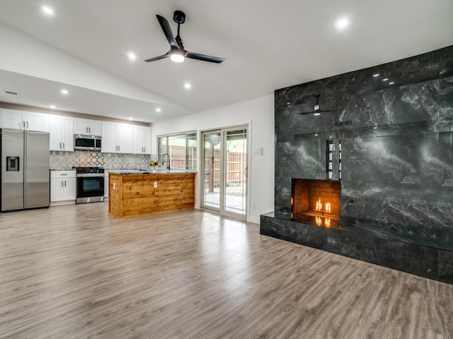940 Windy Meadow Dr, Plano, TX 75023 - living area with a premium fireplace, light wood finished floors, a ceiling fan, lofted ceiling, and recessed lighting