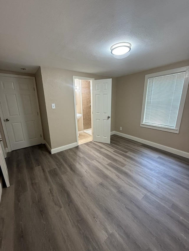 602 Pierson St, Lancaster, TX 75146 - unfurnished bedroom featuring a textured ceiling, dark wood finished floors, and baseboards