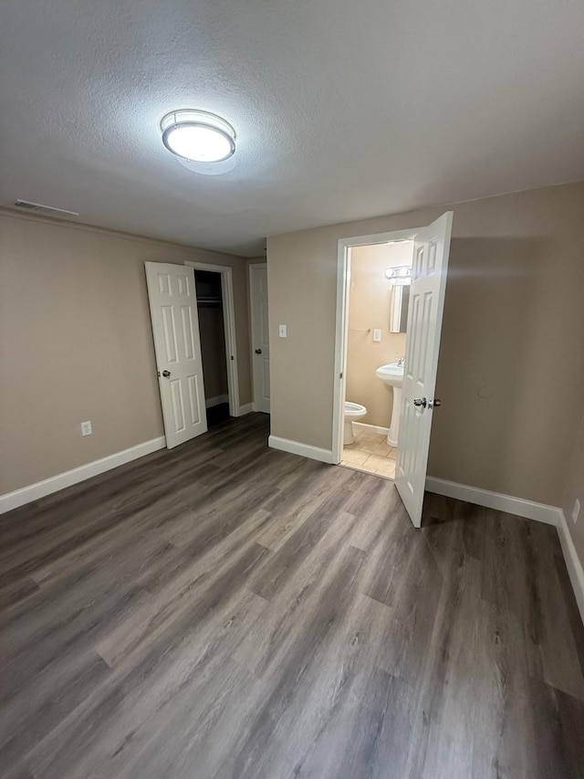 602 Pierson St, Lancaster, TX 75146 - unfurnished bedroom featuring baseboards, a textured ceiling, wood finished floors, a sink, and a closet