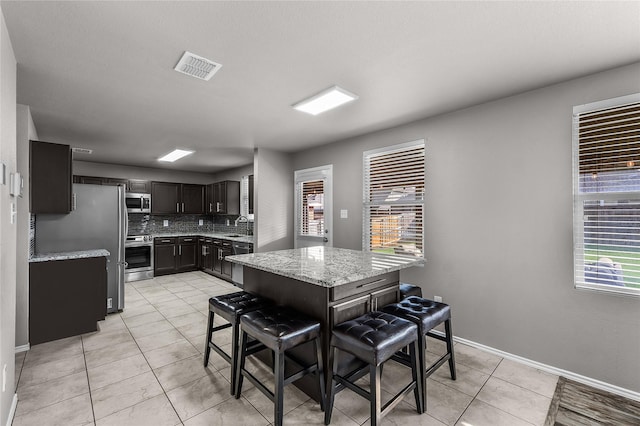 8002 Stowe Springs Ln, Arlington, TX 76002 - kitchen featuring stainless steel appliances, tasteful backsplash, light tile patterned flooring, light stone counters, and a sink