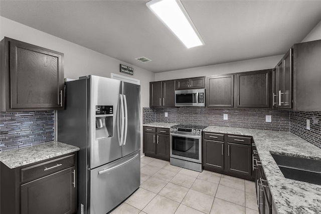 8002 Stowe Springs Ln, Arlington, TX 76002 - kitchen with stainless steel appliances, tasteful backsplash, light tile patterned floors, and light stone counters