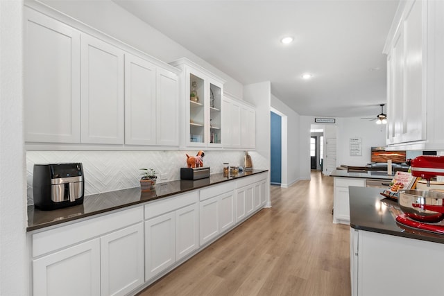 2603 Loxley Dr, Mansfield, TX 76084 - kitchen featuring dark countertops, white cabinets, decorative backsplash, ceiling fan, and light wood-style flooring