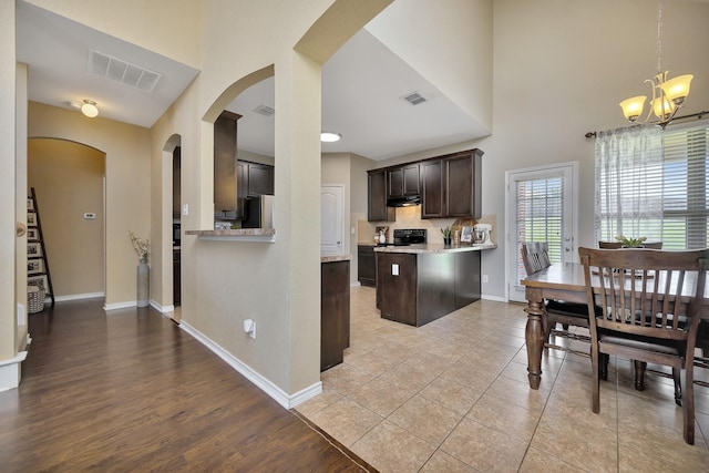4013 Vista Greens Dr, Fort Worth, TX 76244 - kitchen with arched walkways, dark brown cabinets, under cabinet range hood, a chandelier, and baseboards