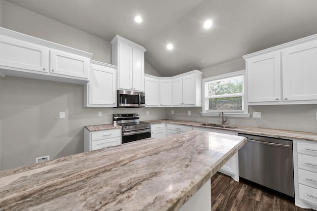 209 NE 6th Ave, Mineral Wells, TX 76067 - kitchen featuring appliances with stainless steel finishes, a sink, white cabinets, lofted ceiling, and light stone counters