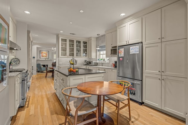 3766 W 4th St, Fort Worth, TX 76107 - kitchen featuring stainless steel appliances, wall chimney range hood, recessed lighting, backsplash, and light wood-style flooring