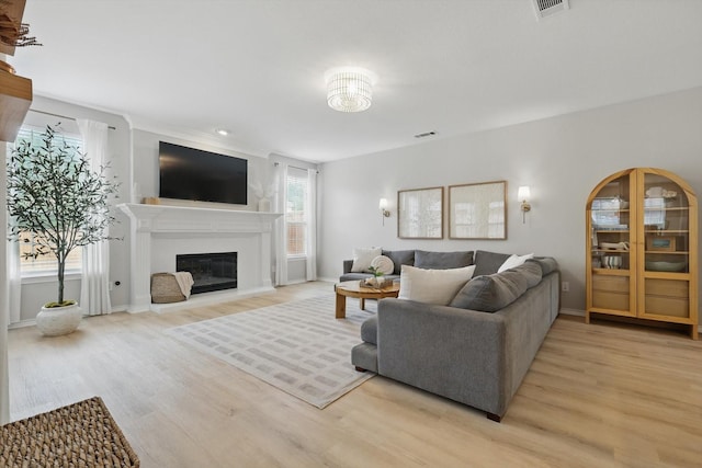 7205 Fair Valley Way, Plano, TX 75024 - living room with light wood-style floors, a glass covered fireplace, and baseboards