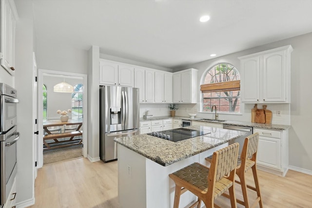 7205 Fair Valley Way, Plano, TX 75024 - kitchen with appliances with stainless steel finishes, a sink, light wood-style floors, a kitchen island, and white cabinetry