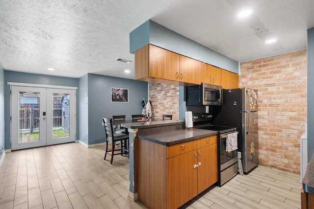 31 W Townhouse Ln Unit 20, Grand Prairie, TX 75052 - kitchen featuring appliances with stainless steel finishes, wood tiled floors, a textured ceiling, dark countertops, and baseboards