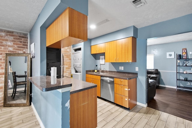 31 W Townhouse Ln Unit 20, Grand Prairie, TX 75052 - kitchen with dishwasher, estacked washer and dryer, a textured ceiling, wood finish floors, and dark countertops