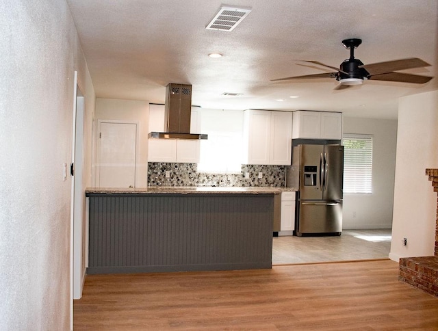 731 E Cherry St, Duncanville, TX 75116 - kitchen with stainless steel fridge with ice dispenser, wall chimney exhaust hood, ceiling fan, white cabinets, and decorative backsplash