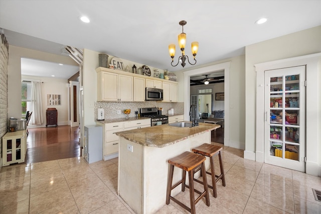 100 Corsicana St, Hillsboro, TX 76645 - kitchen featuring appliances with stainless steel finishes, a sink, a chandelier, light stone countertops, and ceiling fan