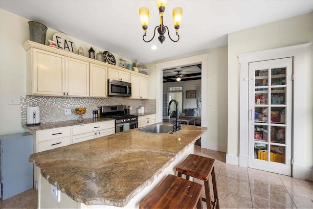 100 Corsicana St, Hillsboro, TX 76645 - kitchen featuring stainless steel appliances, a sink, decorative backsplash, an island with sink, and a chandelier