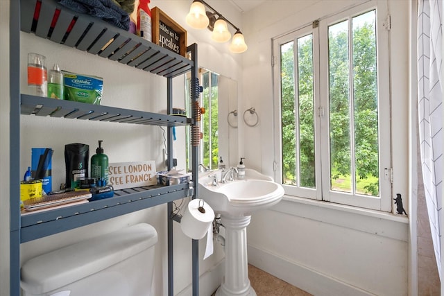 100 Corsicana St, Hillsboro, TX 76645 - bathroom featuring plenty of natural light, toilet, tile patterned flooring, and baseboards