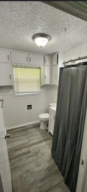 401 Frisco St, Cumby, TX 75433 - bathroom with wood finished floors, toilet, vanity, and a textured ceiling