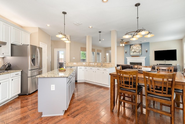 2916 Woods Dr, Plano, TX 75025 - kitchen with stainless steel fridge, a warm lit fireplace, a ceiling fan, open floor plan, and a center island