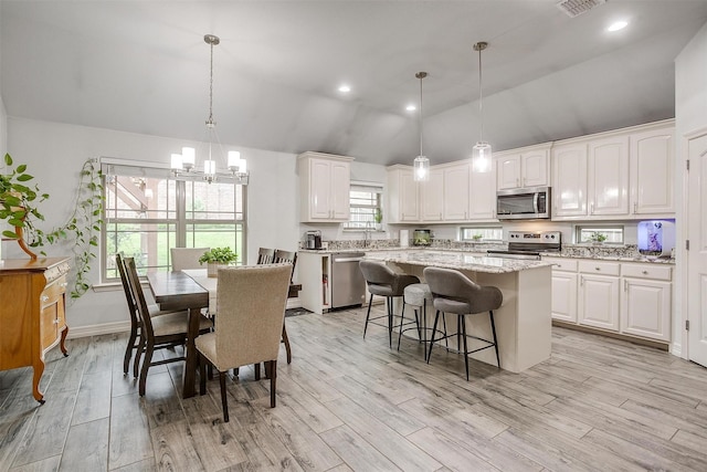 1017 Thistle Hill Trl, Weatherford, TX 76087 - kitchen with appliances with stainless steel finishes, a center island, white cabinets, a breakfast bar area, and high vaulted ceiling