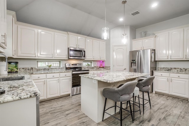 1017 Thistle Hill Trl, Weatherford, TX 76087 - kitchen with appliances with stainless steel finishes, white cabinets, vaulted ceiling, a kitchen island, and light wood finished floors