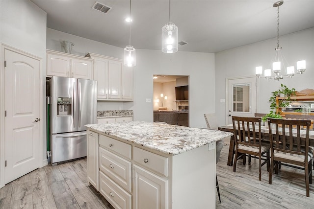 1017 Thistle Hill Trl, Weatherford, TX 76087 - kitchen with stainless steel fridge with ice dispenser, light wood-type flooring, a kitchen island, and light stone counters