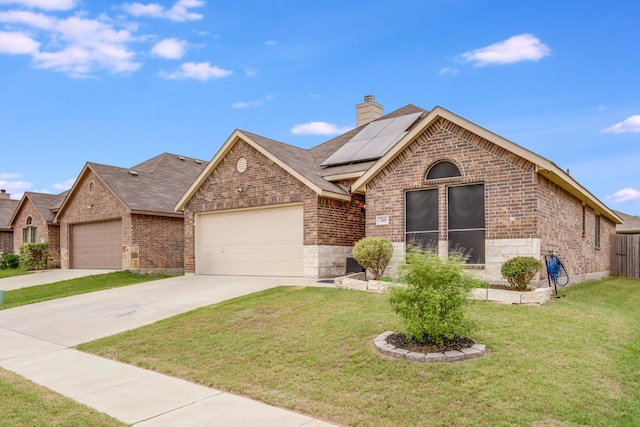 318 Green Meadows Rd, Wilmer, TX 75172 - view of front of property featuring brick siding, an attached garage, a front yard, and roof mounted solar panels