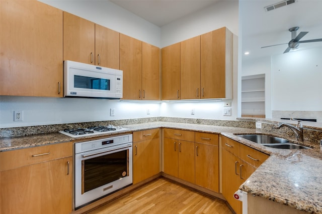 4302 Gilbert Ave, Dallas, TX 75219 - kitchen with white appliances, a sink, light stone counters, light wood-style flooring, and a ceiling fan