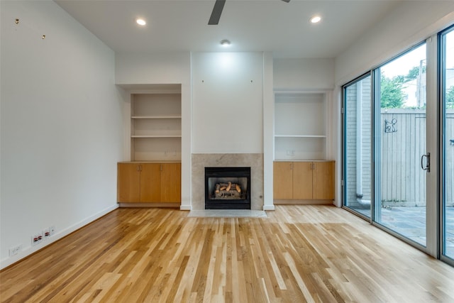 4302 Gilbert Ave, Dallas, TX 75219 - unfurnished living room with a tiled fireplace, wood finished floors, a ceiling fan, built in features, and recessed lighting