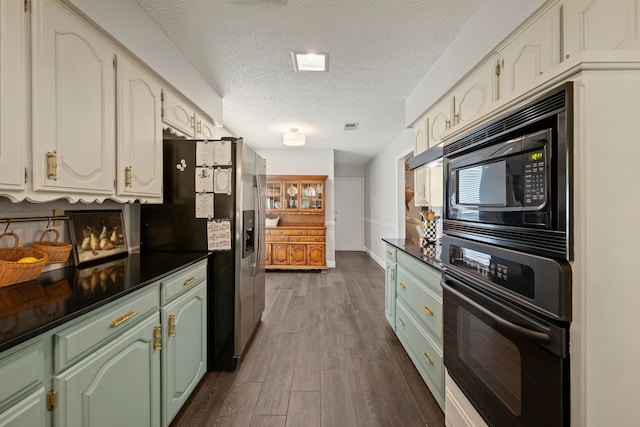 7529 Mapleleaf Dr, North Richland Hills, TX 76182 - kitchen with black appliances, dark countertops, a textured ceiling, dark wood finished floors, and green cabinets