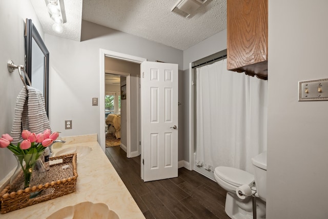 7529 Mapleleaf Dr, North Richland Hills, TX 76182 - bathroom featuring wood finished floors, double vanity, a textured ceiling, toilet, and baseboards