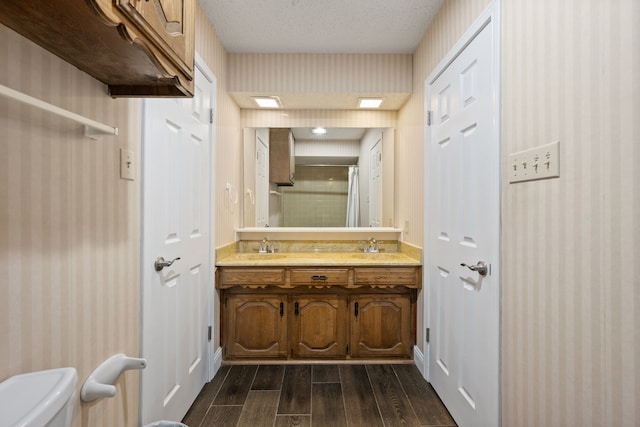 7529 Mapleleaf Dr, North Richland Hills, TX 76182 - bathroom featuring wood finished floors, wallpapered walls, double vanity, a shower with door, and toilet