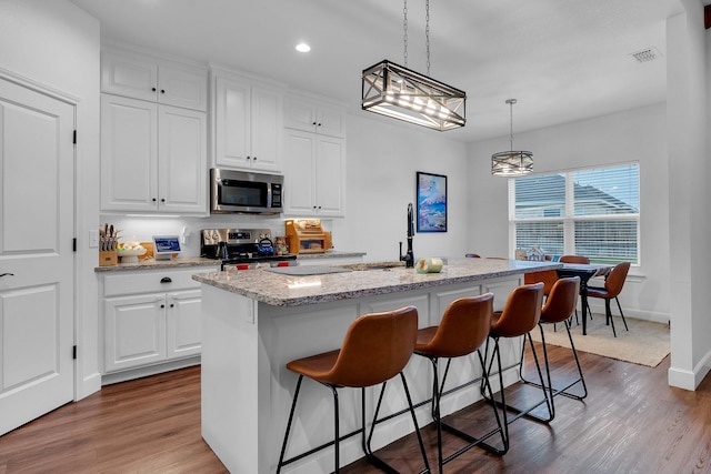 138 Lake Ridge Ct, Abilene, TX 79602 - kitchen with stainless steel appliances, a sink, dark wood finished floors, a kitchen breakfast bar, and white cabinetry