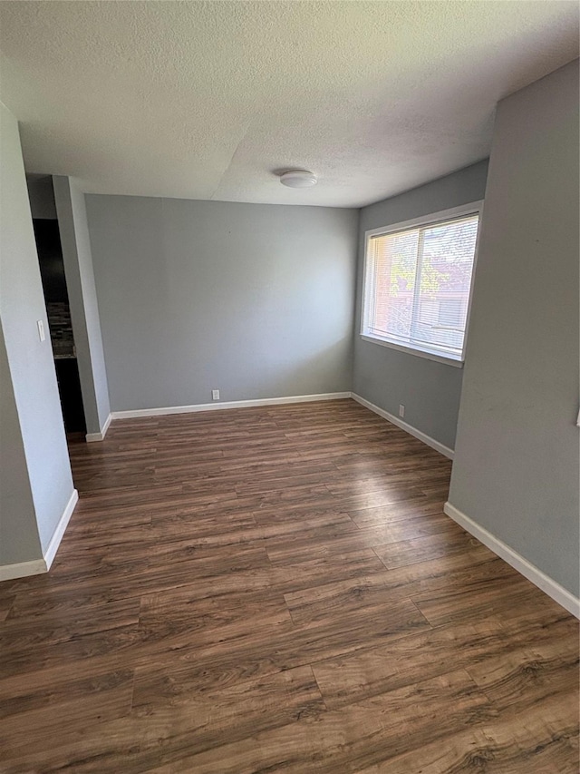 2804 W Walnut Hill Ln, Irving, TX 75038 - empty room featuring a textured ceiling, dark wood-style floors, and baseboards