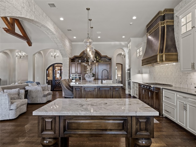 4905 Reserve Ct, Parker, TX 75002 - kitchen with a center island with sink, arched walkways, custom range hood, decorative backsplash, and glass insert cabinets