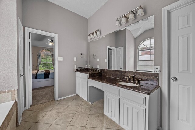 7421 Buckskin Ct, Fort Worth, TX 76137 - ensuite bathroom featuring double vanity, tile patterned floors, a relaxing tiled tub, a ceiling fan, and baseboards