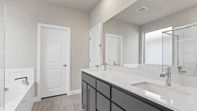 11213 Orchard Ln, Justin, TX 76247 - bathroom featuring a bath, double vanity, wood finished floors, and baseboards