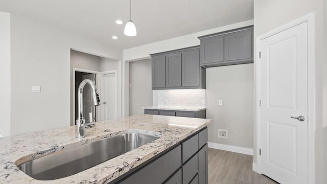 11213 Orchard Ln, Justin, TX 76247 - kitchen featuring a sink, light stone counters, decorative light fixtures, light wood-style flooring, and recessed lighting
