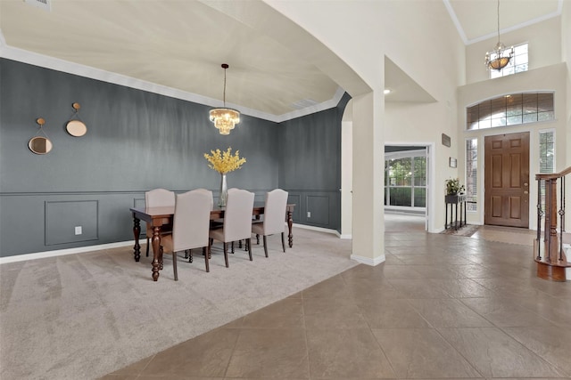 621 Maize Rd, Murphy, TX 75094 - carpeted dining area featuring a chandelier, a decorative wall, crown molding, baseboards, and a high ceiling