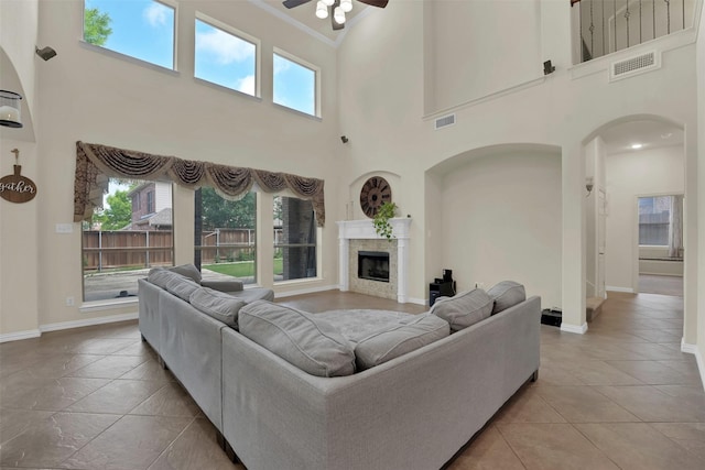 621 Maize Rd, Murphy, TX 75094 - living room featuring ceiling fan, a towering ceiling, arched walkways, baseboards, and a fireplace