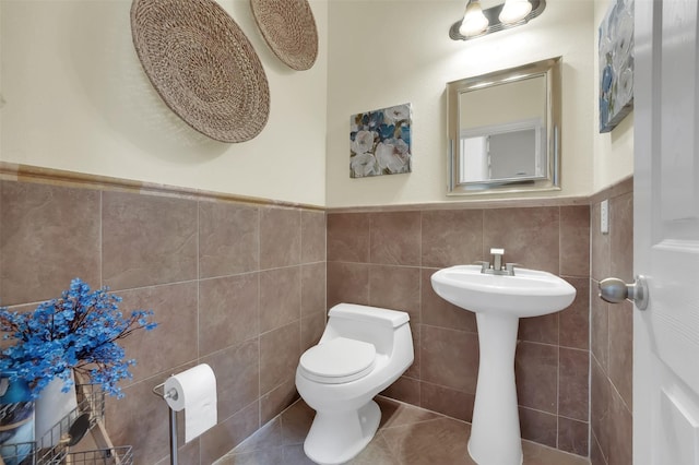 621 Maize Rd, Murphy, TX 75094 - half bathroom with toilet, tile walls, a wainscoted wall, tile patterned flooring, and a sink