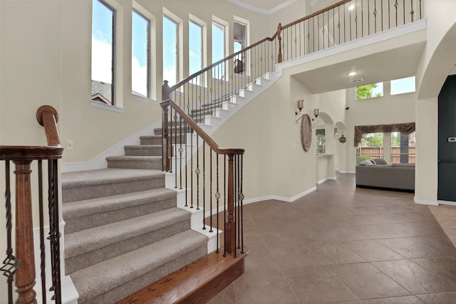 621 Maize Rd, Murphy, TX 75094 - stairs with arched walkways, a towering ceiling, baseboards, tile patterned flooring, and ornamental molding