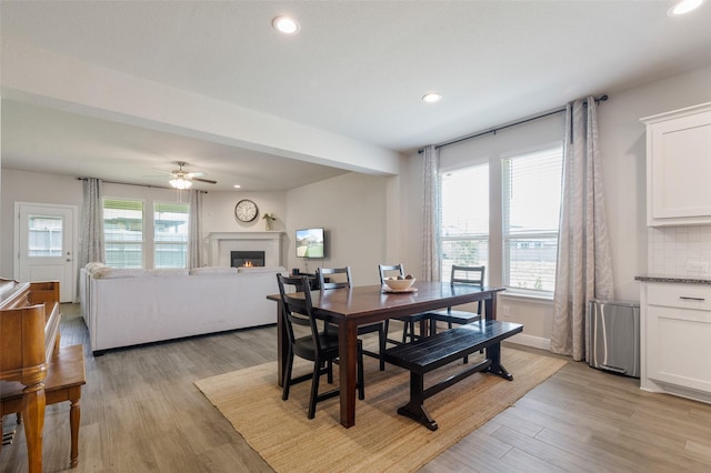 1713 Brindle St, Justin, TX 76247 - dining room featuring a glass covered fireplace, light wood finished floors, ceiling fan, and recessed lighting