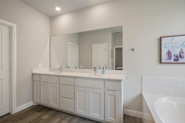 1713 Brindle St, Justin, TX 76247 - full bath featuring double vanity, wood finished floors, a garden tub, and baseboards