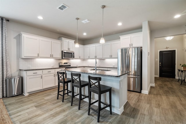 1713 Brindle St, Justin, TX 76247 - kitchen featuring stainless steel appliances, a sink, light wood-style flooring, white cabinetry, and recessed lighting