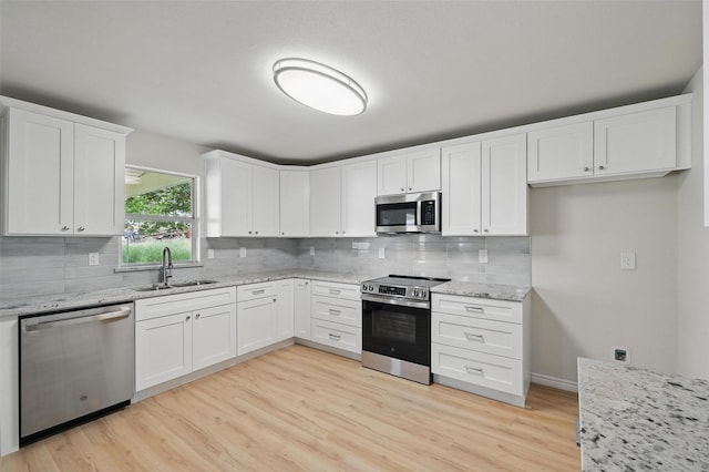 1126 Mazourka Dr, Arlington, TX 76001 - kitchen featuring appliances with stainless steel finishes, a sink, tasteful backsplash, and light wood-style floors