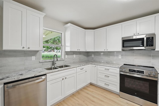 1126 Mazourka Dr, Arlington, TX 76001 - kitchen with stainless steel appliances, a sink, decorative backsplash, white cabinets, and light wood-style flooring