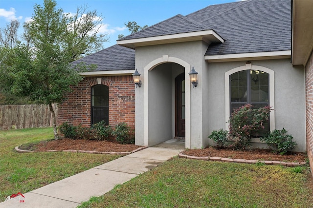 9445 N Pointe Cir, Greenwood, LA 71033 - view of exterior entry with a shingled roof, stucco siding, and brick siding
