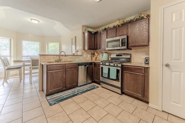 522 E Lanett Dr, Desoto, TX 75115 - kitchen with stainless steel appliances, a sink, decorative backsplash, a peninsula, and light tile patterned flooring