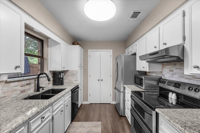 1210 Kay Dr, Weatherford, TX 76086 - kitchen featuring under cabinet range hood, stainless steel appliances, a sink, dark wood-type flooring, and white cabinetry